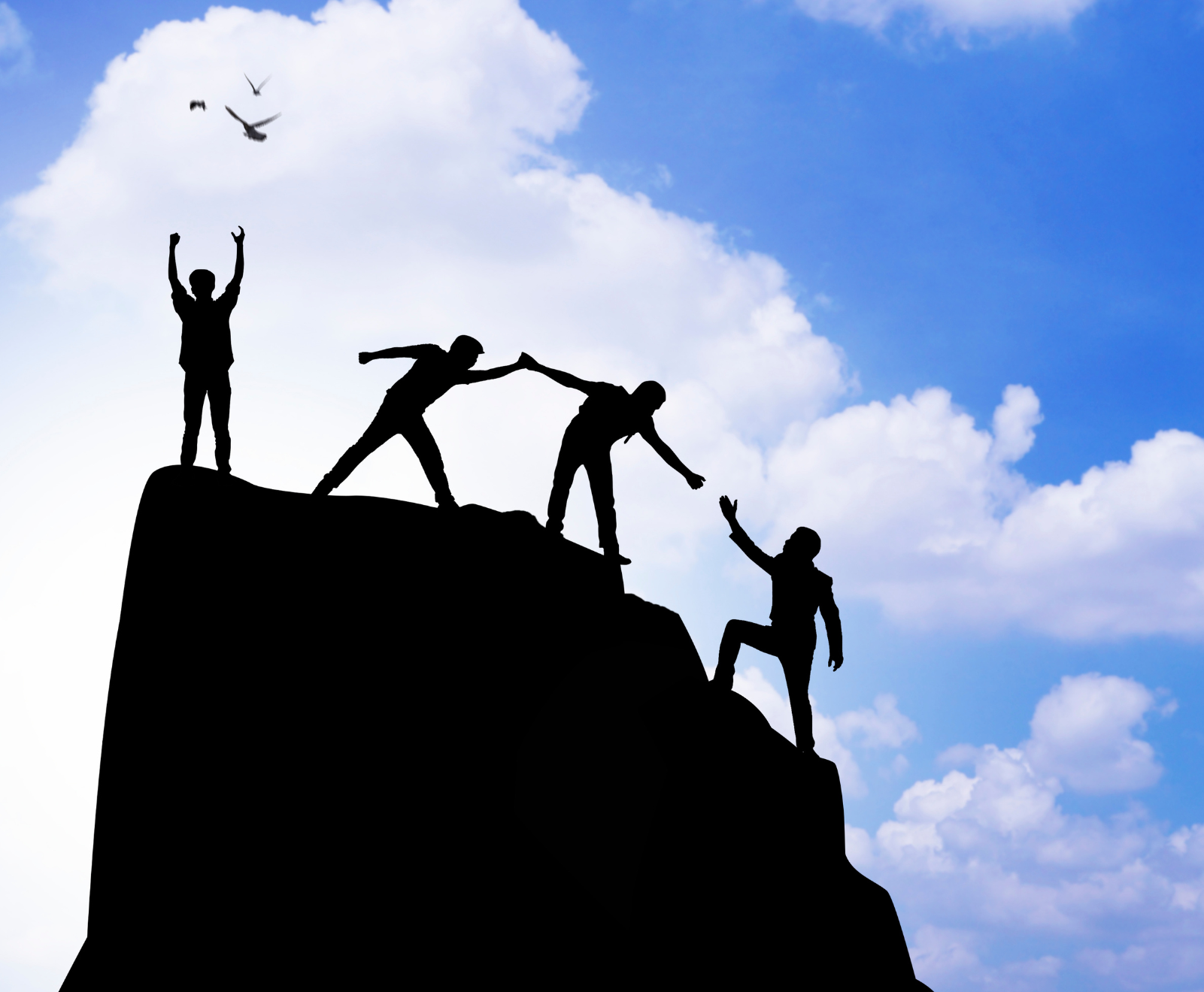 Four people climbing a mountain top, three of them reaching out to support one another, in front of a blue sky with clouds.